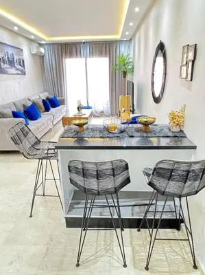 a living room with a bar with three chairs at Appart au Cœur de Gueliz in Marrakech