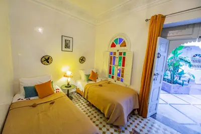 a bedroom with two beds and a window at Riad LAMDINA in Marrakech