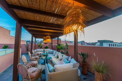 a rooftop patio with couches and tables and chairs at Riad LAMDINA in Marrakech