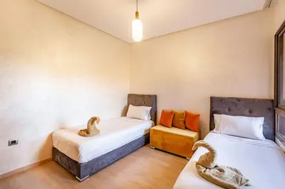 a room with two beds and a chair in it at Stunning Prestigia Escape Poolside Views in Marrakech