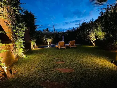 a yard with two lawn chairs and lights at night at Villa avec piscine chauffée en option Palmeraie in Marrakech