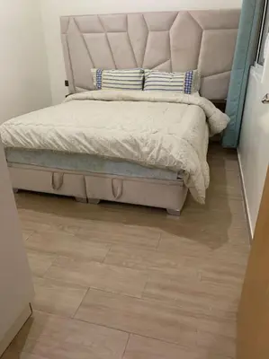 a bedroom with a bed with a headboard and a wooden floor at Appartement Moderne bien équipée reservation Juste pour les familles est les couples mariés in Marrakech