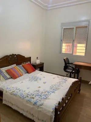 a bedroom with a bed and a desk and a window at Appartement Moderne bien équipée reservation Juste pour les familles est les couples mariés in Marrakech