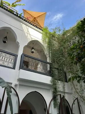 a white building with a balcony with an umbrella at Riad Dar Fannan en exclusivité in Marrakech