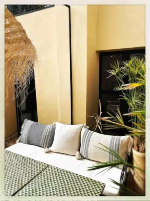 a couch with pillows sitting in a room with plants at Riad Dar Fannan en exclusivité in Marrakech