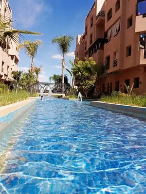 a swimming pool in a resort with palm trees and buildings at Chambre de luxe avec piscine in Marrakech