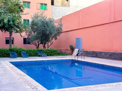 a swimming pool with two chairs and a building at Luxoria Home - Pool & 3 min To Gueliz in Marrakech
