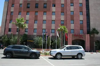 two cars parked in a parking lot in front of a building at Hotel Relax Marrakech in Marrakech