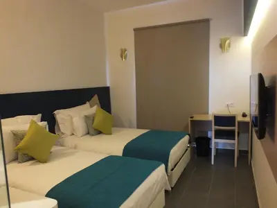 a hotel room with two beds and a desk at Hotel Relax Marrakech in Marrakech