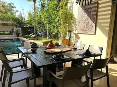 a dining room with a table and chairs and a pool at Palais Bali in Marrakech