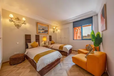 a hotel room with two beds and a chair at Piscine Hivernage plein Centre in Marrakech