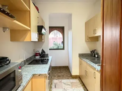 a kitchen with wooden cabinets and a counter top at Paradis à marrakech Grande Piscine in Marrakech