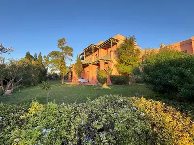 a large building with a yard with flowers in front of it at Paradis à marrakech Grande Piscine in Marrakech