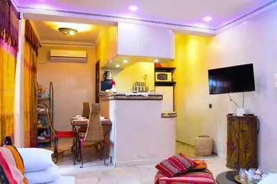 a living room with a kitchen and a table with chairs at Appartement Riad élégant chic au cœur de Guéliz in Marrakech