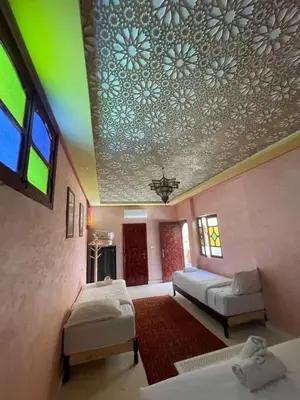 a room with two beds and a ceiling with flowers at Riad Naffar in Marrakech