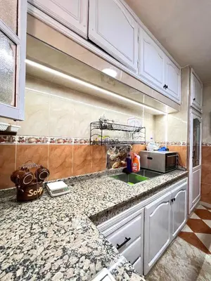 a kitchen with white cabinets and granite counter tops at Cozy Apartment near airport in Marrakech