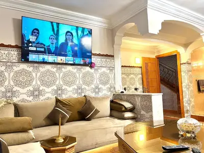 a living room with a couch and a tv on a wall at Cozy Apartment near airport in Marrakech