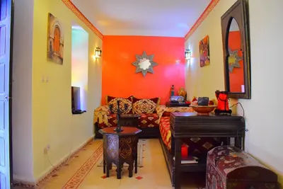 a living room with orange walls and a couch at Riad les ANGES DU DESERT in Marrakech