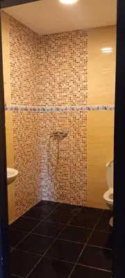 a bathroom with a toilet and a tiled wall at Jnan chrifiya in Marrakech
