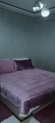 a bed in a bedroom with a purple blanket at Jnan chrifiya in Marrakech