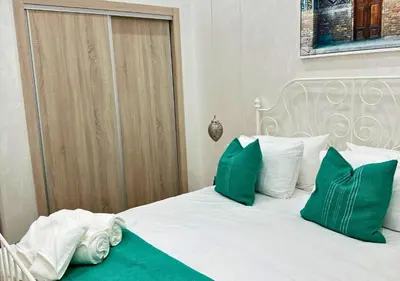 a bed with green and white pillows on it at Sérénité Berbère Appartement centre Marrakech in Marrakech