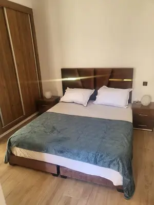 a bedroom with a large bed with a wooden headboard at Cozy Nour in Marrakech