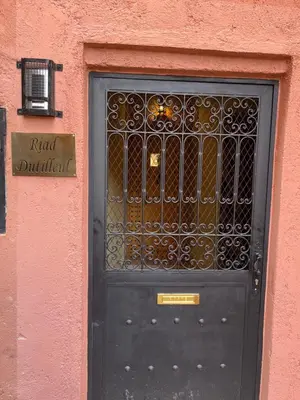 a black door with a metal gate on a pink building at Riad Dutilleul in Marrakech
