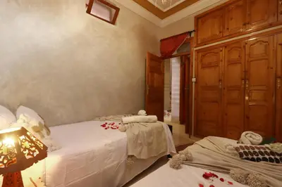 a bedroom with two beds with white sheets and a lamp at Riad Blue in Marrakech