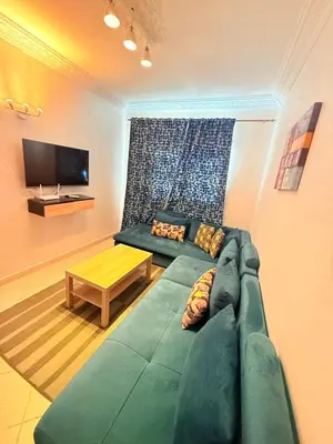 a living room with a green couch and a tv at Appart FAMILY lumineux & terrasse privé in Marrakech