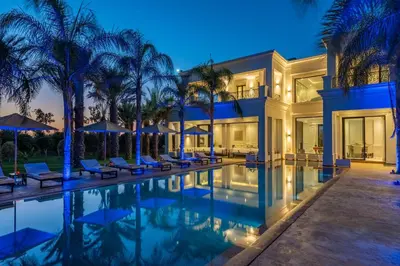 a villa with a swimming pool at night at White Mansion in Tameslouht