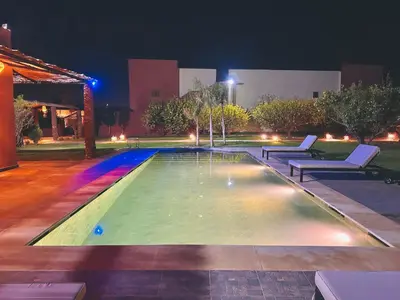 a swimming pool at night with two lounges around it at Villa piscine privée sans vis à vis, 20 min du Centre - Fibre Optique Wifi in Marrakech