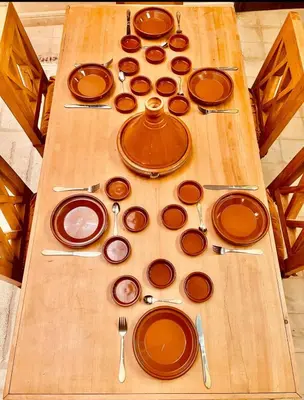 a wooden table with plates and utensils on it at Edwiria Marrakech in Marrakech