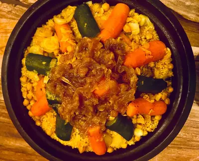 a black bowl of food with meat and vegetables at Edwiria Marrakech in Marrakech