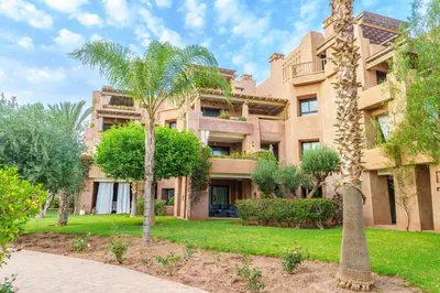 an apartment building with palm trees in front of it at Appartement de charme residence avec piscine WiFi in Marrakech