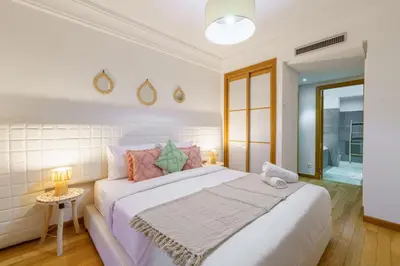 a white bedroom with a large bed with pink pillows at Appartement de charme residence avec piscine WiFi in Marrakech