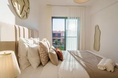 a bedroom with a bed with white pillows and a window at Elegance and Serenity at Noria Golf and Pool view in Marrakech