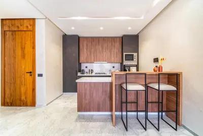 a kitchen with wooden cabinets and a counter with stools at Bohemian Style in Hyper-Center - Optical Fiber in Marrakech