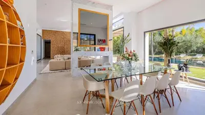 a dining room with a glass table and white chairs at VilLA AYDEN in Marrakech