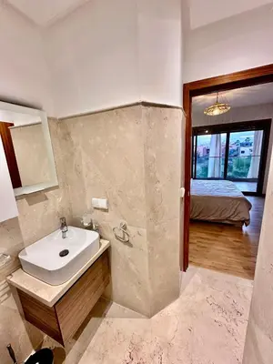 a bathroom with a sink and a bed in a room at Pearl Garden Appart 2 chambres Luxe Cosy Moderne in Marrakech