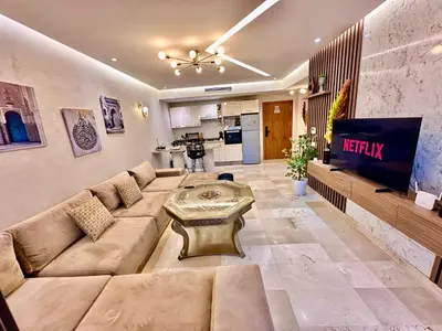 a living room with a large couch and a tv at Pearl Garden Appart 2 chambres Luxe Cosy Moderne in Marrakech