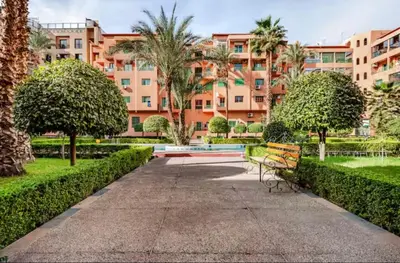 a park with a bench in front of a building at Appart hôtel avec piscine in Marrakech