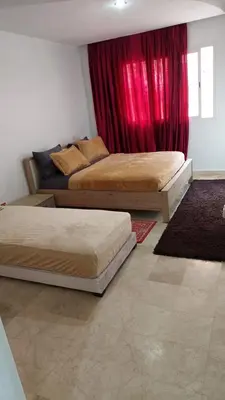 two beds in a bedroom with red curtains at le spacieux 37 pour familles face gare CTM Hivernage in Marrakech