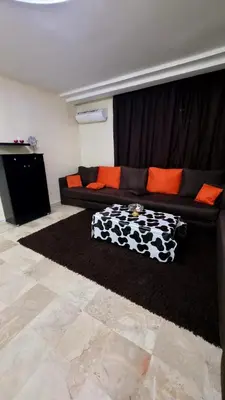 a living room with a black couch with orange pillows at le spacieux 37 pour familles face gare CTM Hivernage in Marrakech