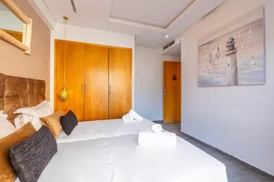 a bedroom with a white bed with a wooden headboard at Grand appartement deux terrasses in Marrakech