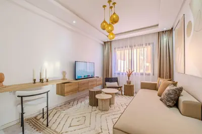 a living room with a couch and a tv at Grand appartement deux terrasses in Marrakech