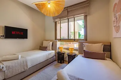 a living room with two beds and a tv at Elevated Elegance A Stylish Golf Atlas Apartment in Marrakech