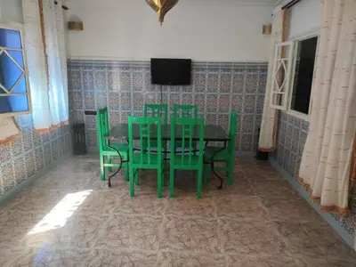 a dining room with green chairs and a table at 5 min Aéroport Appartement avec Terrasse et Grand Appartement in Marrakech