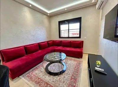 a red couch in a living room with a table at Chic Appartement Marrakech in Marrakech