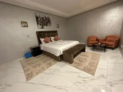 a bedroom with a bed and a couch and chairs at Villa à la palmeraie in Marrakech