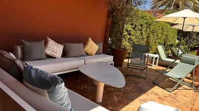 a living room with a couch and chairs and an umbrella at Dar Nadim sur le Golf de Samanah in Marrakech